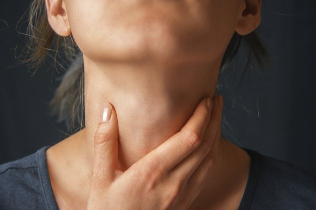 Woman holds her throat, sore throat