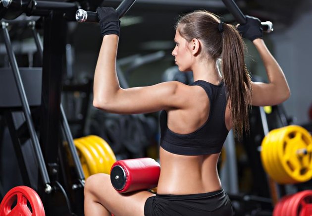 Attractive young woman working out on weight-lifting training machine