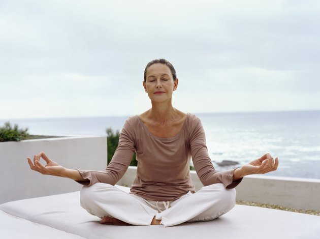 Senior Woman Meditating in the Lotus Position with the Sea in the Background