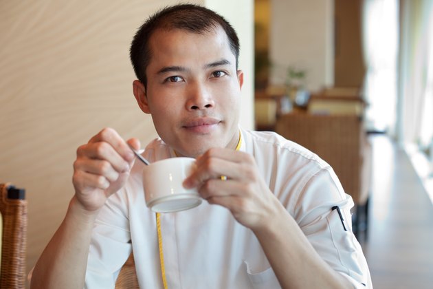 Chinese chef wearing uniform enjoying coffee break in restaurant cafe