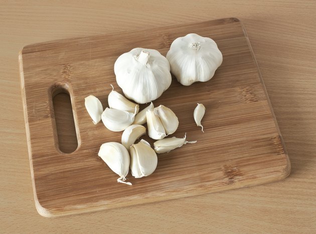 Garlic on brown cutting bamboo board used for cooking.