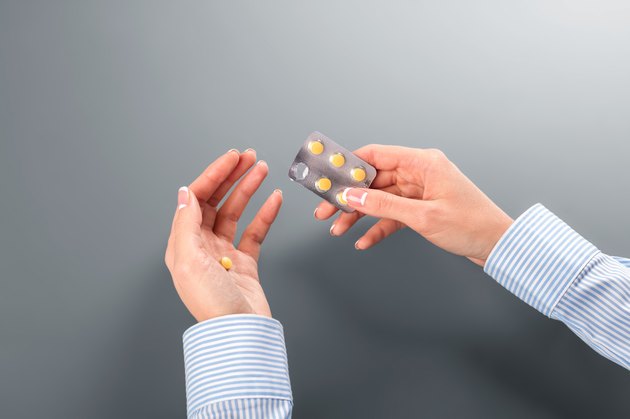 Female taking pill from blister.