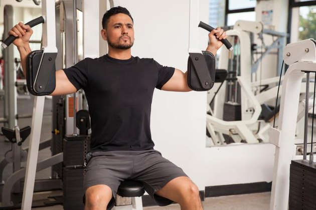 Young man working out at the gym on a peck deck machine