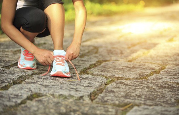 young fitness woman tying shoelaces on trail