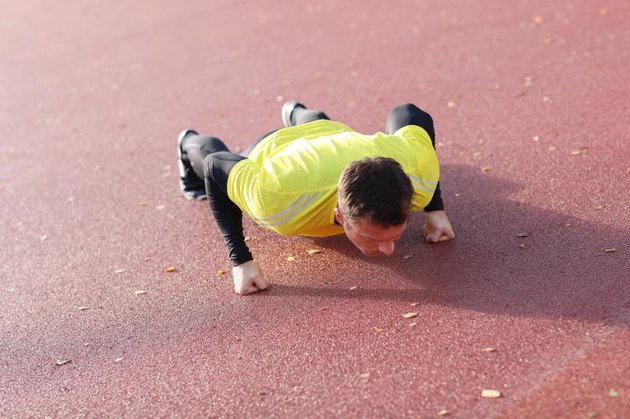 Man exercises outdoors with knuckle push-ups..