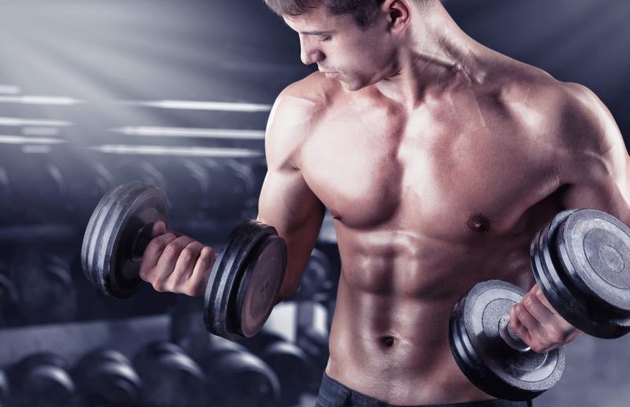 在健身房的肌肉年轻男子举重的特写