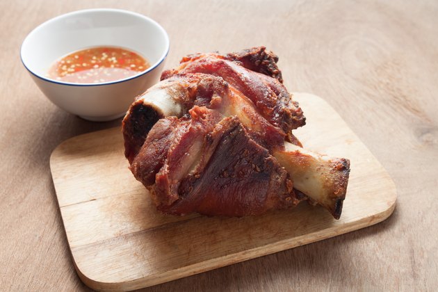 German BBQ pork knuckle served with sauce on wood background