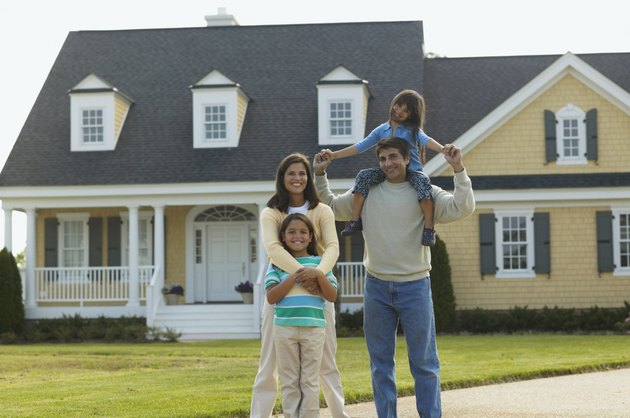 Young couple standing with their children in front of a house