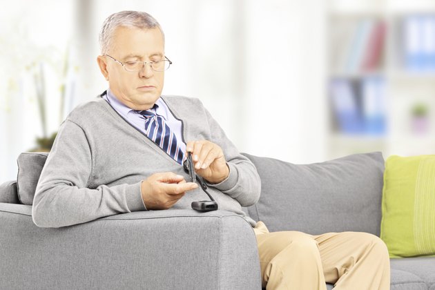 Mature on sofa measuring sugar level at home