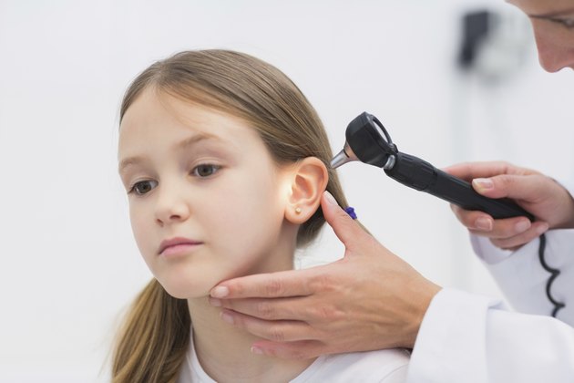 General practitioner auscultating the ear of a patient