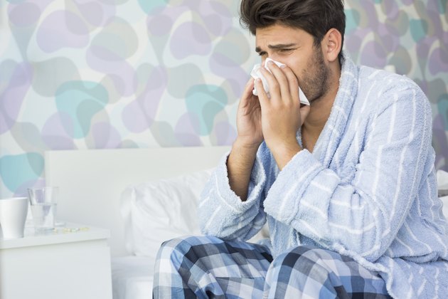 Sick man blowing his nose in tissue paper