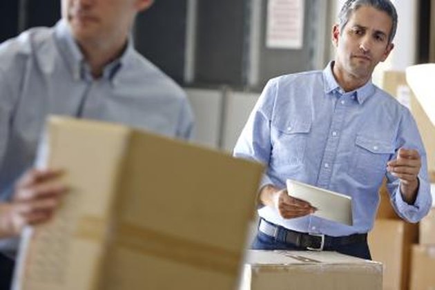Manager Using Headset In Distribution Warehouse Taking Notes Concentrating