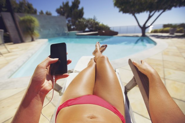 Woman holding a smart phone by the pool