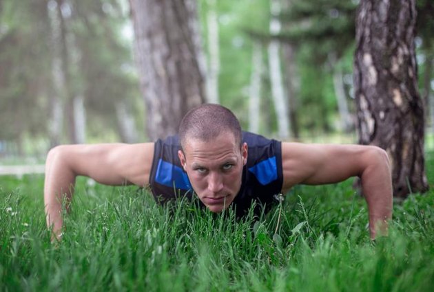 strong sports men doing push ups outdoors in grass field