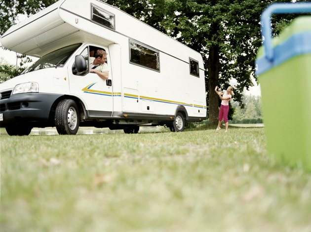 Young Girl Directing Her Father as he Reverses a Motor Home into a Parking Space in a Field