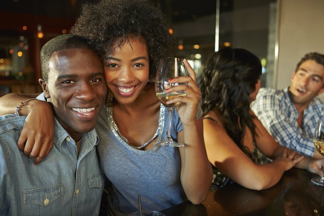 Couple Enjoying Drink At Bar With Friends