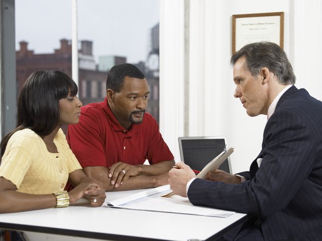 Doctor Explaining a Document to a Couple at His Clinic