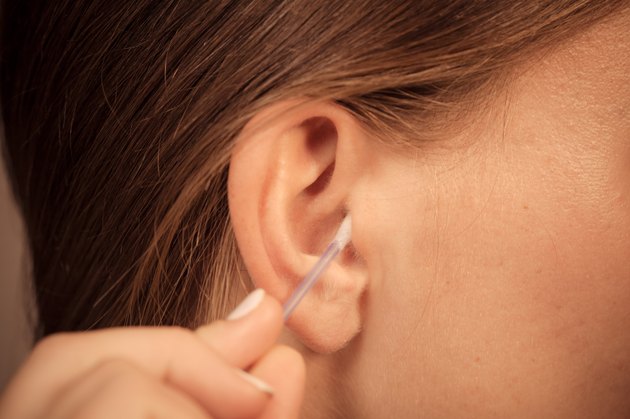 Woman cleaning ear with cotton swabs closeup