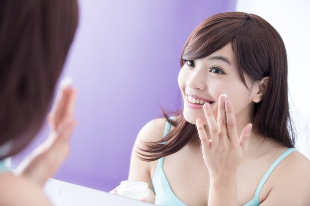 Smile woman applying moisturizer cream