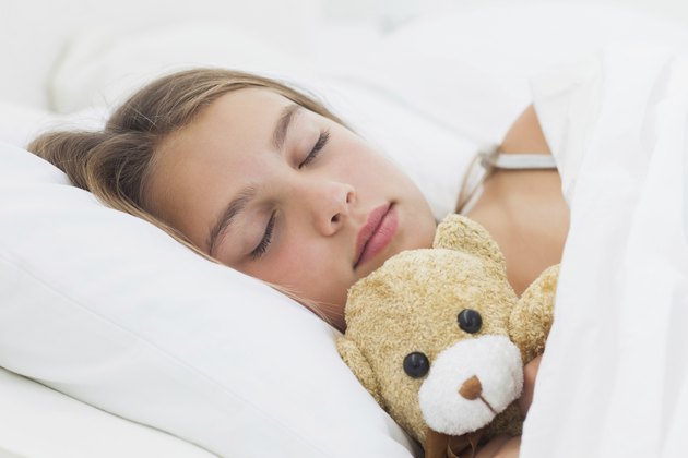 Cheerful girl sleeping with her teddy bear
