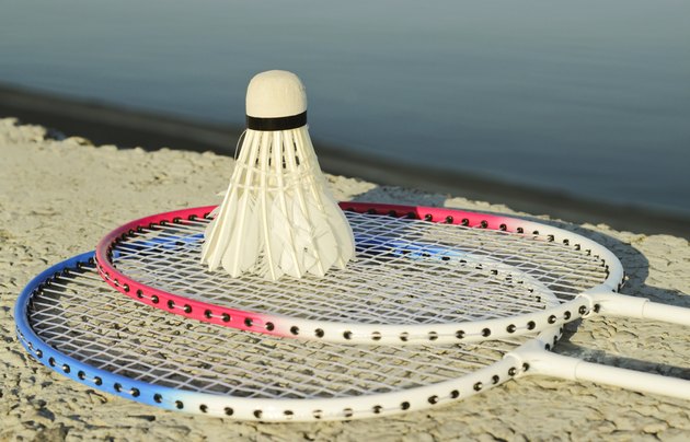 Badminton racquets with shuttlecock on a stone bench against the
