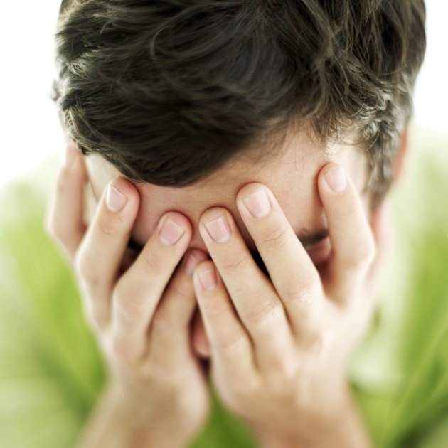 close-up of a young man holding his face between his hands