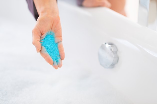closeup on young woman adding bath salt in bathtub