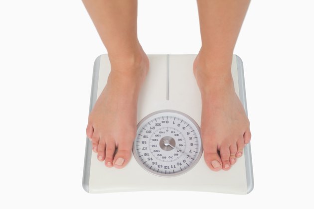 Female feet standing on a white scales