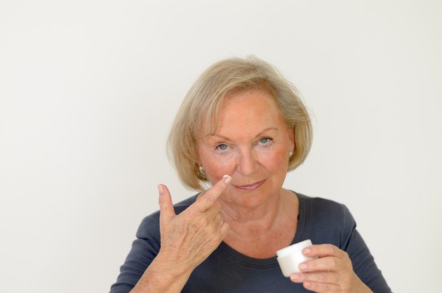 Attractive middle-aged woman applying creme