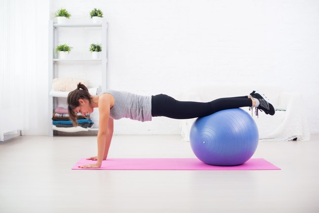 Woman doing push-ups on the floor with fit ball