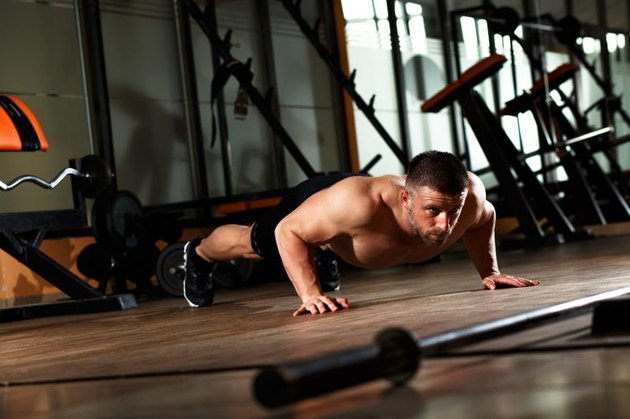 Muscular man doing a pushups at gym.