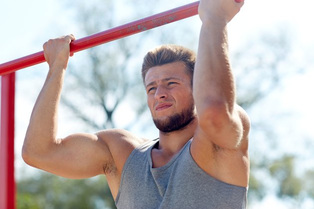 young man exercising on horizontal bar outdoors