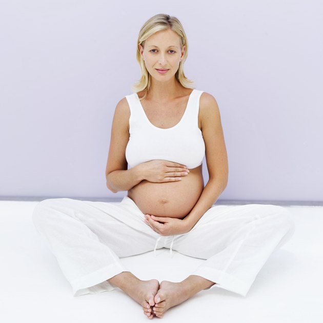 pregnant woman sitting on floor with her hands on stomach