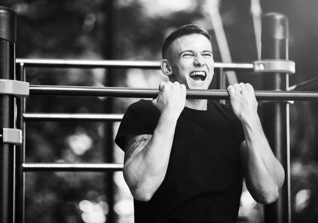Young man doing pull ups on horizontal bar outdoors, workout, sport concept.