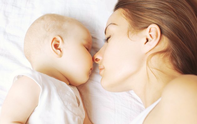 Baby and mother sleeping together on the bed