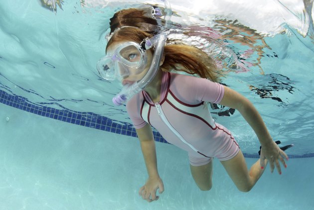 child swimming underwater in pool