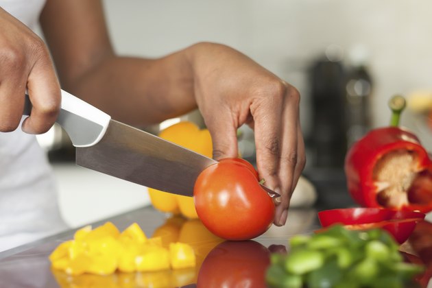 African American womans hand slicing a tomatoe