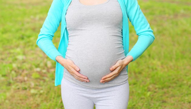 Pregnant young woman outdoors in summer day closeup