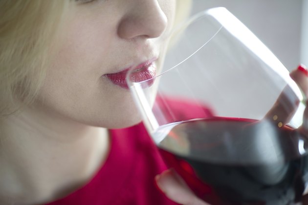 Woman drinking red wine with red lips - close portrait