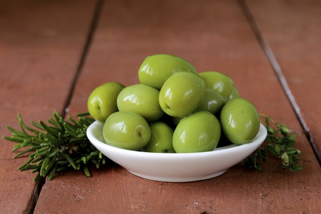 green marinated olives in bowl on a wooden table
