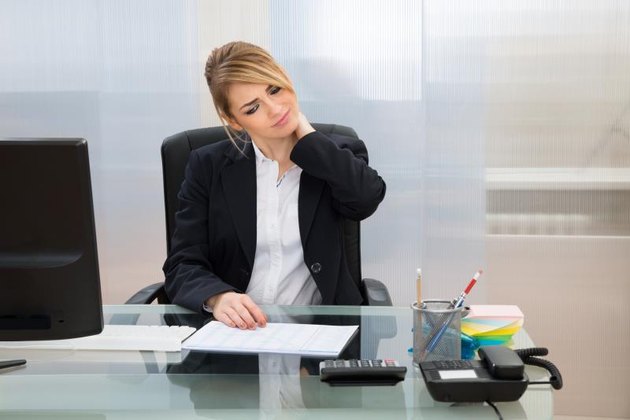 Portrait Of Young Businesswoman Suffering From Neckache In Office