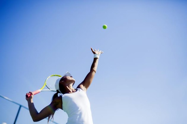 Beautiful female tennis player serving outdoor