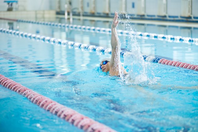 Young girl in goggles swimming front crawl stroke style