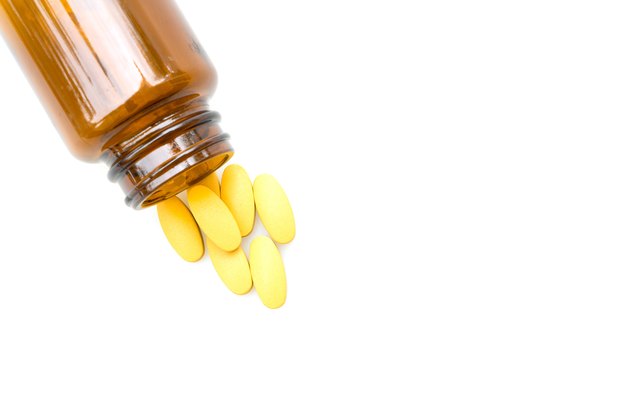 Vitamin tablets and a brown bottle on white