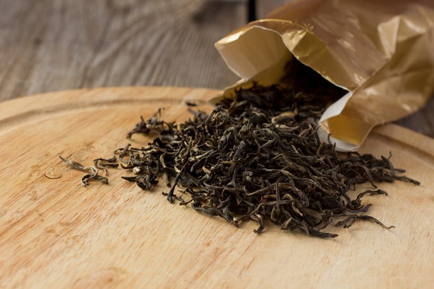 Dry white tea leaves on wooden plate
