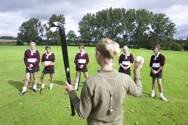 Coach holding field hockey stick and ball team