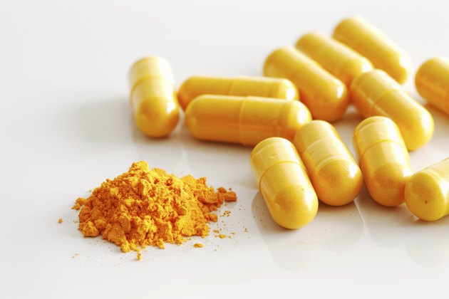 Handful of turmeric capsules with one spilled out