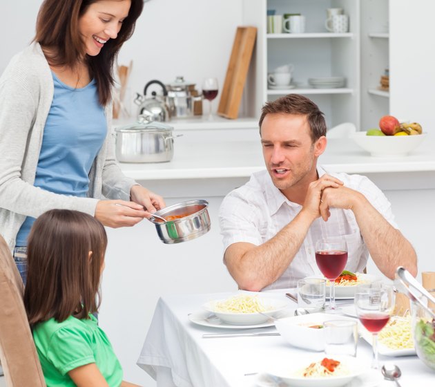 Proud dad talking to his daughter while her mother giving her pasta sauce
