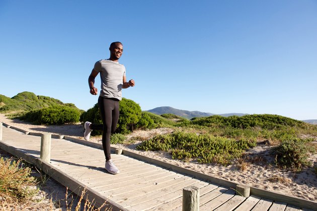 Healthy young african man running on path at the beach