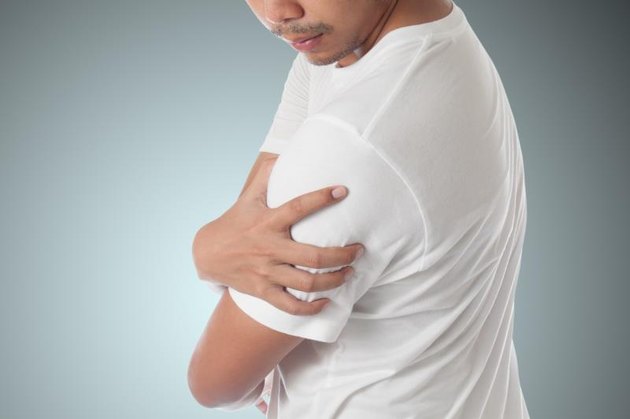man having shoulder pain on blue background